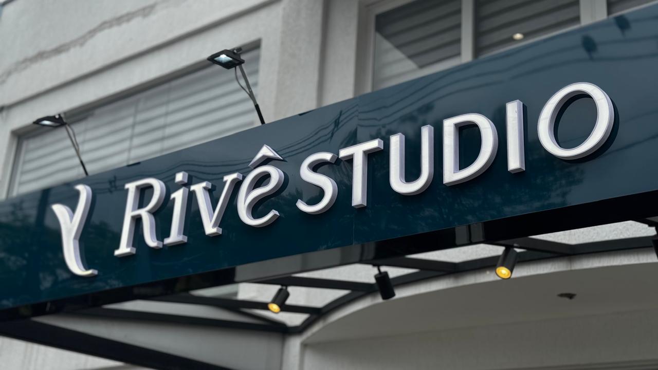 Letreiro da fachada do Rivê Studio em azul petróleo com letras prateadas