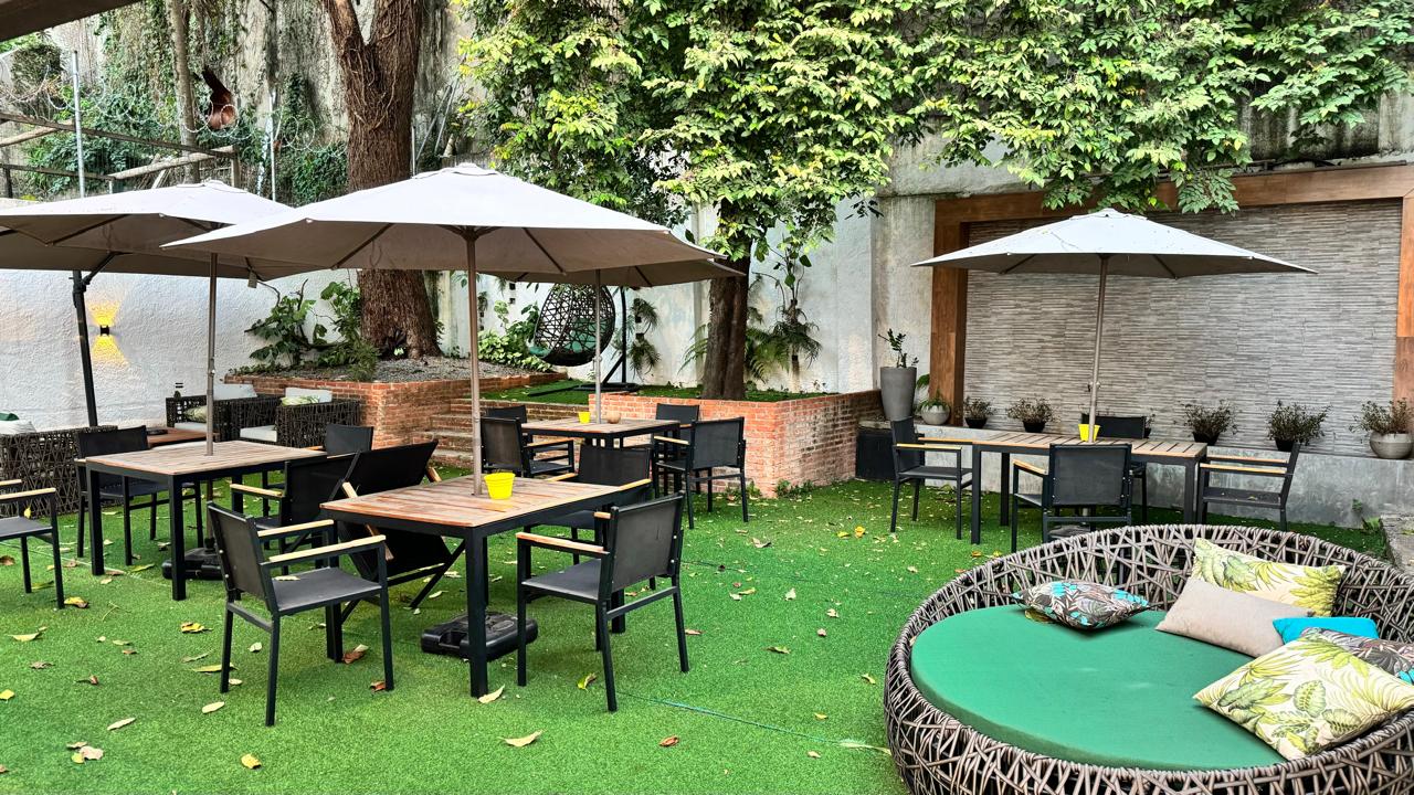 Jardim do Rivê Studio com mesas, guarda-sóis e muito verde