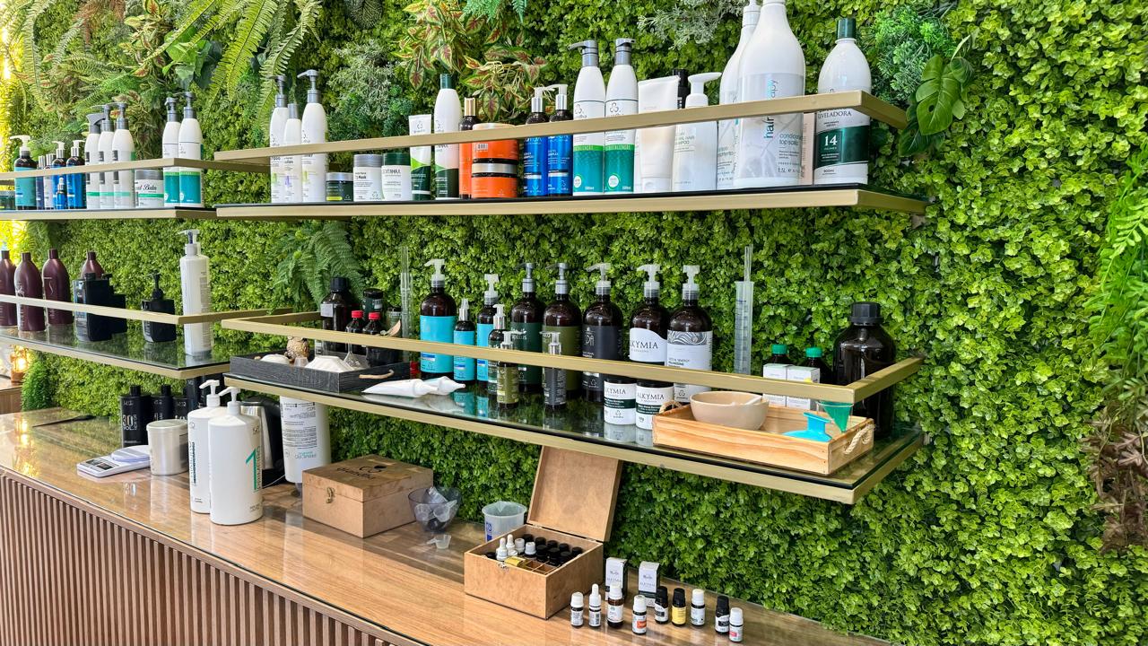 Parede viva de plantas com prateleiras e produtos de cuidado no Rivê Studio